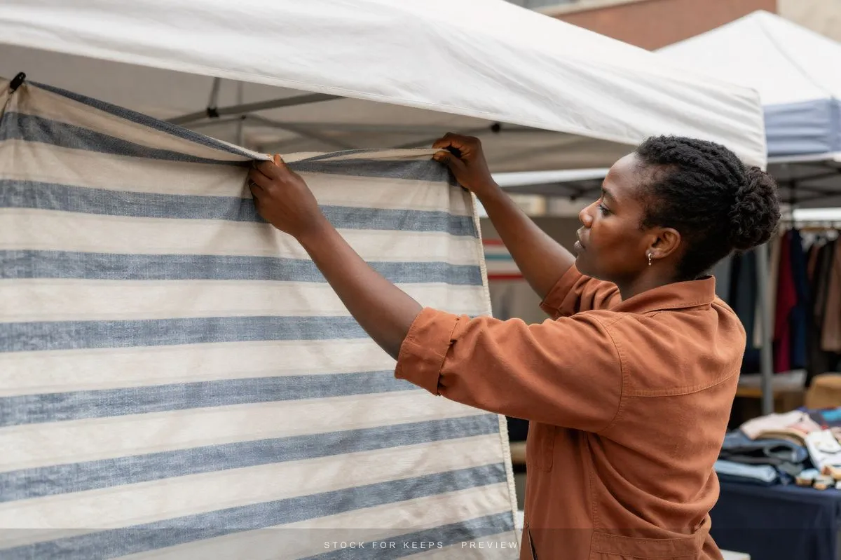 An independent maker arranging fabric at a market stall